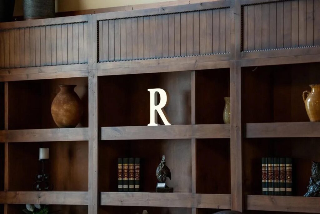 Rustic wooden bookshelf with decorative pottery and classic books at Running Y Resort.