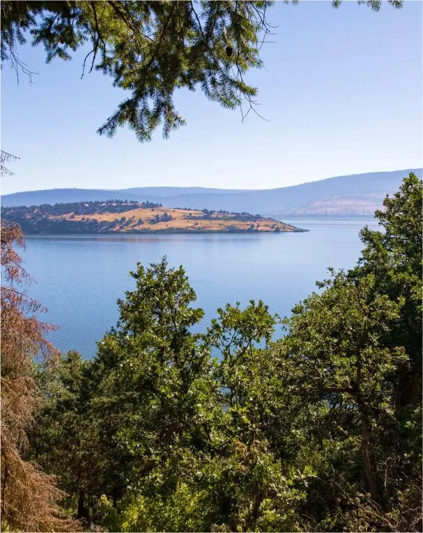 Serene lake view at Running Y Resort surrounded by lush greenery and rolling hills.