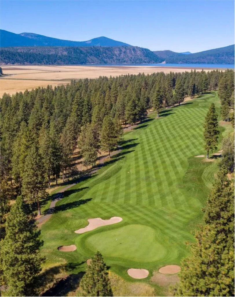 Rolling golf course fairway at Running Y Resort with mountain views and mountain lake in background.