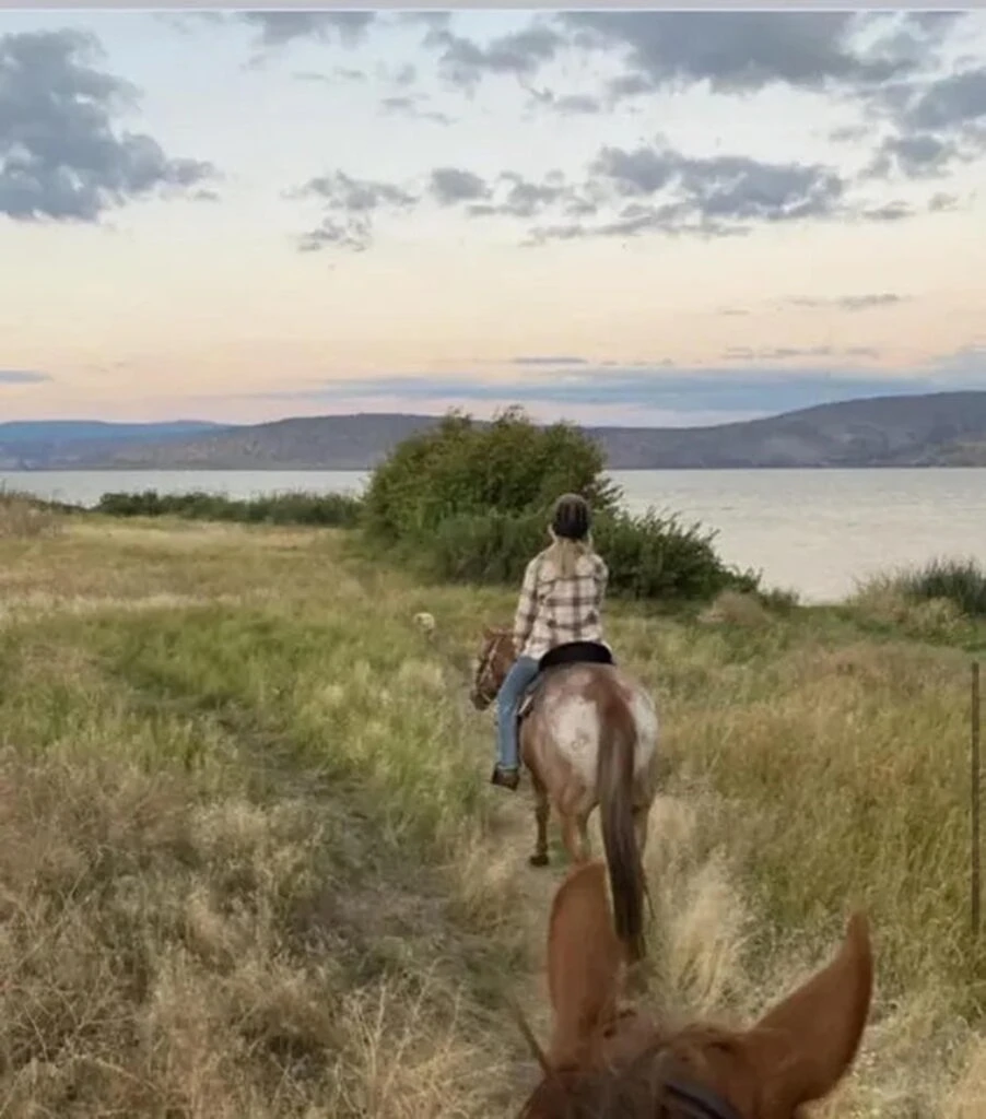 Tranquil horseback riding experience at Running Y Resort overlooking a lake and scenic landscape.