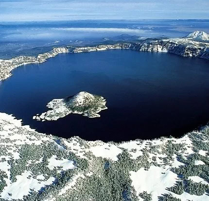 Aerial view of Crater Lake at Running Y Resort in winter with snow-covered landscape.